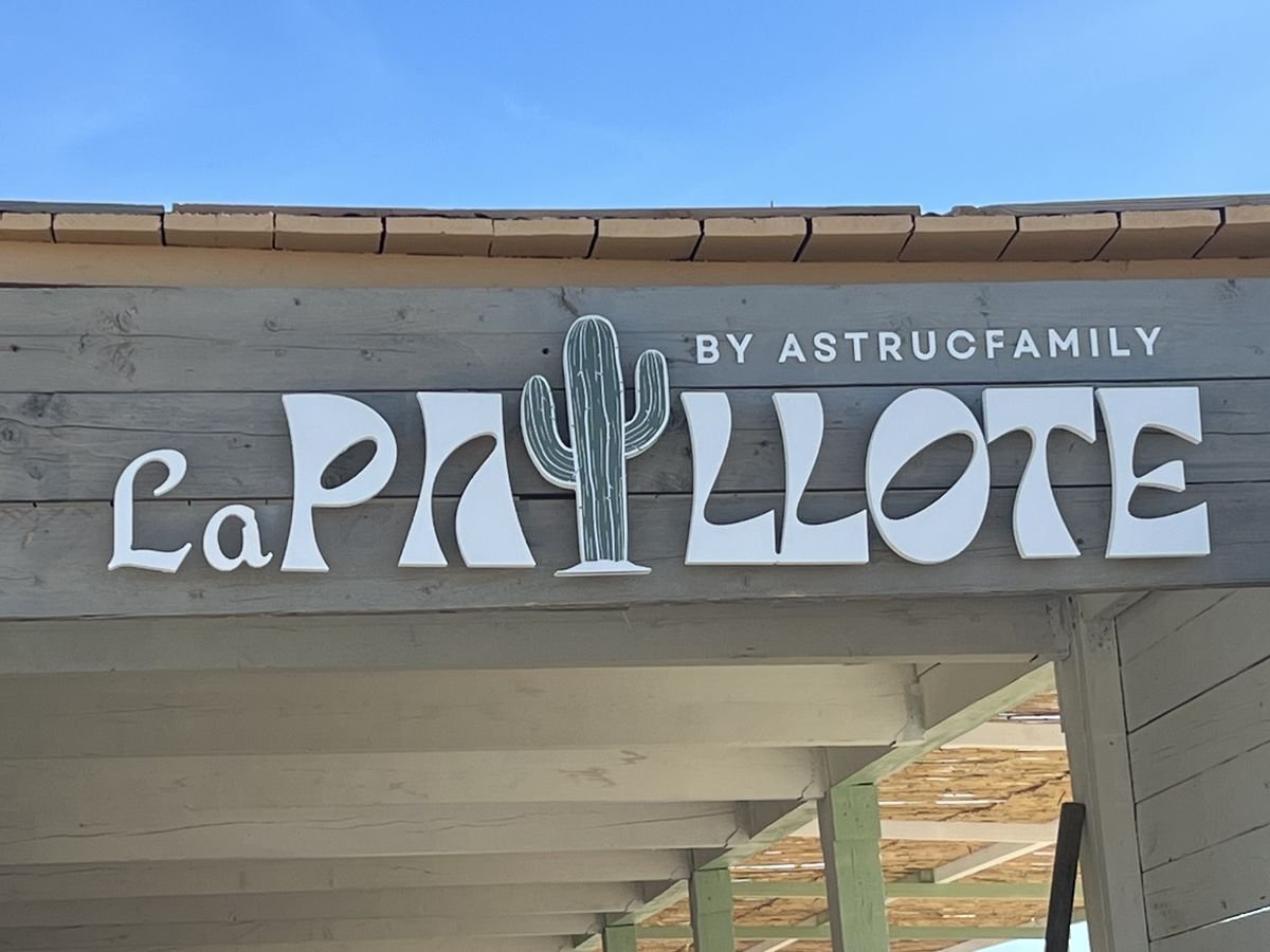 Enseigne de restaurant de plage en lettres découpées blanches « La Paillote » avec un cactus, sur fronton en bois